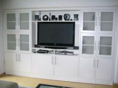 The built-in cabinet shown here presents a large television encompassed by a combination of solid and frosted inset glass doors. Nicely complemented by contemporary bar pulls, it holds a lot, fits right and looks good.
